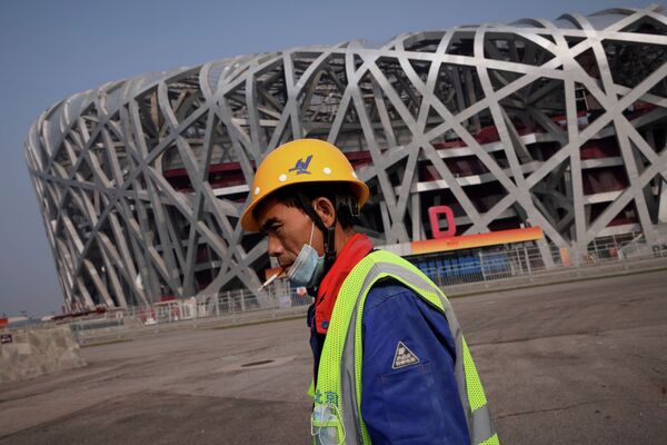 Рабочий возле Национального стадиона Птичье гнездо, где пройдет церемония открытия зимних Олимпийских игр в Пекине - Sputnik Казахстан