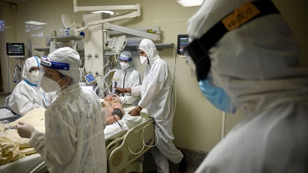 Врачи в защитных костюмах работают с пациентом в палате реанимации в больнице с коронавирусом  - Sputnik Казахстан