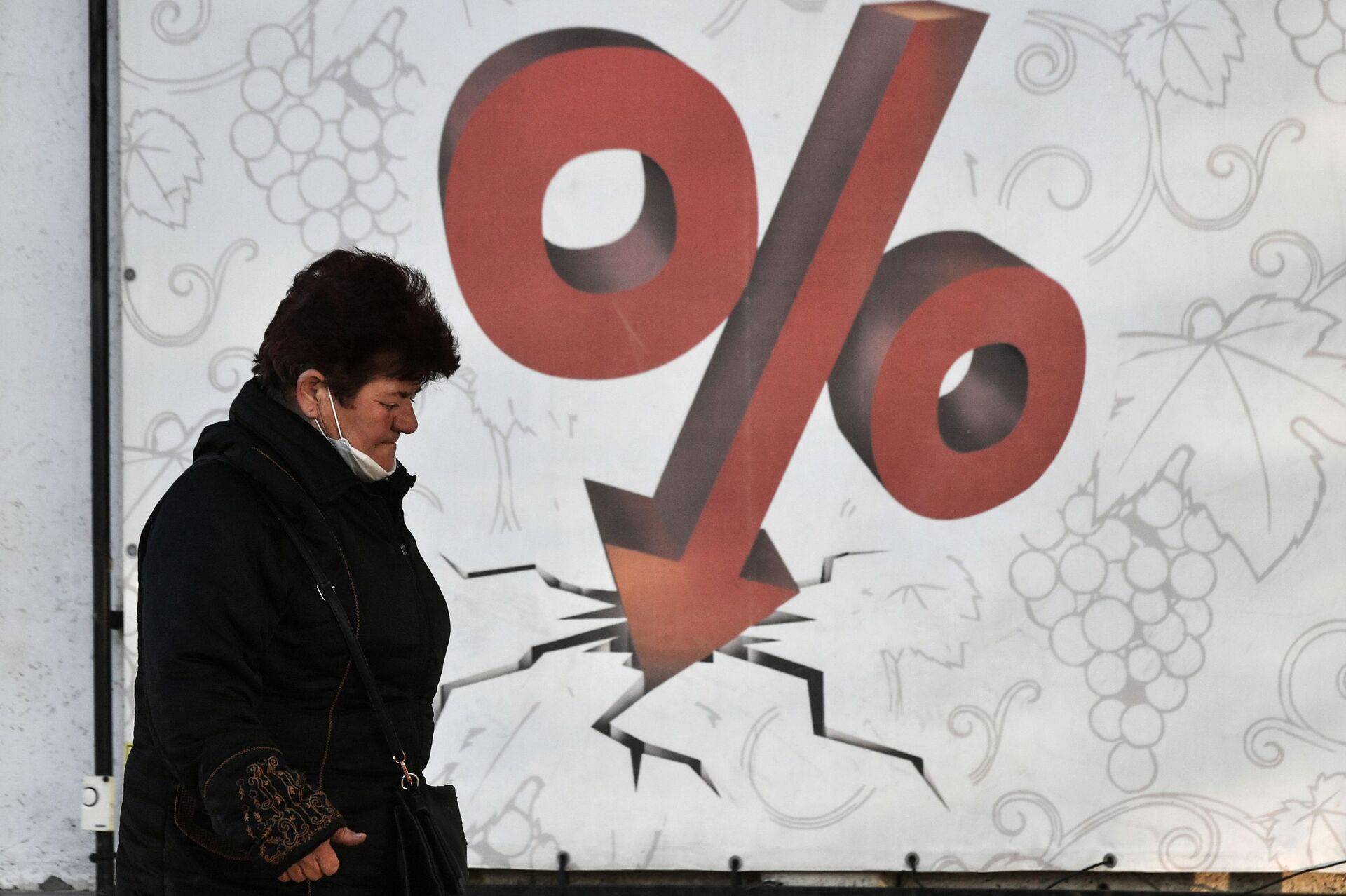 Женщина проходит мимо билборда со знаком процента  - Sputnik Казахстан, 1920, 20.03.2024