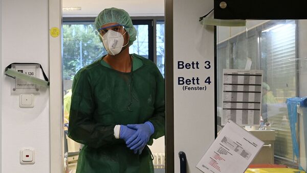 Медик в защитном костюме стоит в дверях отделения реанимации - Sputnik Казахстан