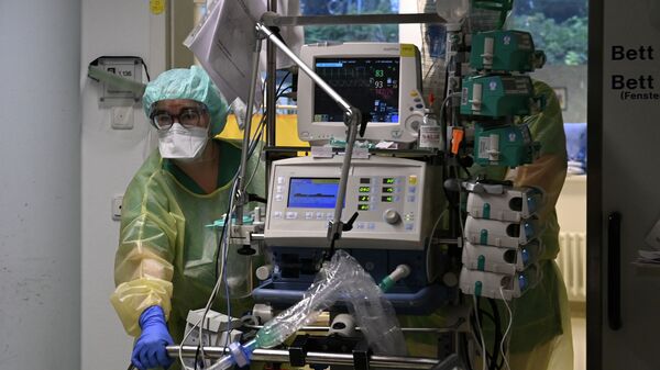 Медики в защитных костюмах перевозят пациента, подключенного к аппаратуре, в палату реанимации больницы с коронавирусом  - Sputnik Казахстан