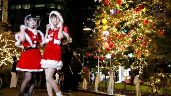 Девушки в костюмах Санта-Клауса фотографируются на фоне рождественских иллюминаций в Токио, Япония - Sputnik Казахстан