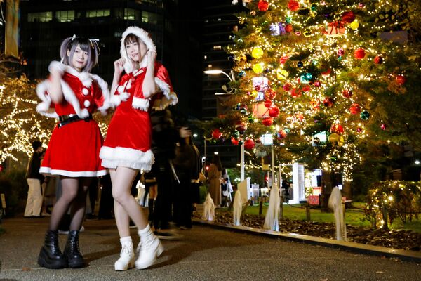 Токиода Санта-Клаус костюмін киген қыздар жаңа жылдық иллюминация жанында суретке түсіп тұр, Жапония.  - Sputnik Қазақстан