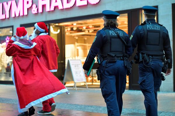 Полицейские сопровождают туристов в нарядах Санта-Клауса на торговой улице в Дрездене.   - Sputnik Казахстан