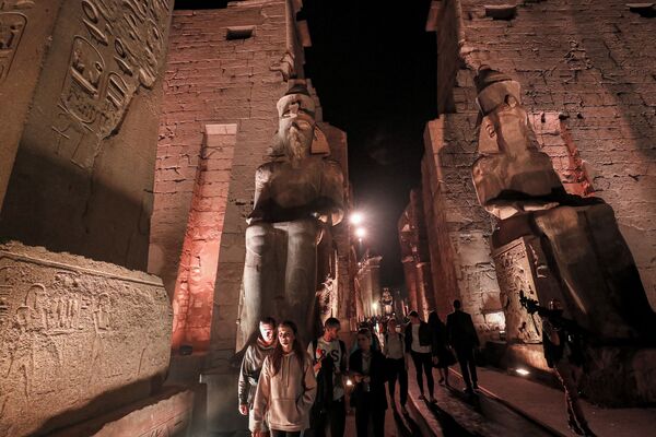 Посетители проходят мимо статуй древнеегипетского фараона Рамзеса II в храме Луксор - Sputnik Казахстан