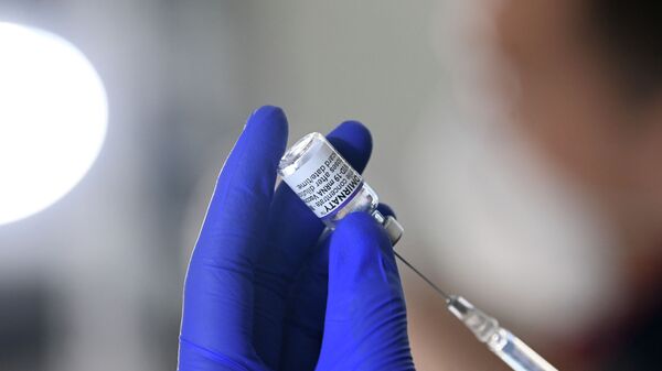 Медик набирает вакцину от коронавируса в шприц - Sputnik Қазақстан