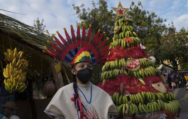 Танцовщица рядом с рождественской елкой, собранной из бананов, на площади Мурильо во время церемонии зажжения рождественской елки в Ла-Пасе, Боливия.  - Sputnik Казахстан