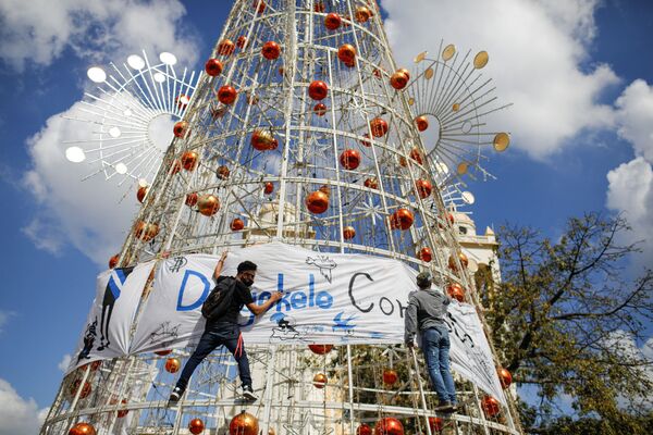 Активисты вешают баннер на елку во время акции протеста против действий правительства президента Сальвадора Найиба Букеле, таких как использование биткойнов и правовые реформы для продления его срока, в Сан-Сальвадоре. - Sputnik Казахстан