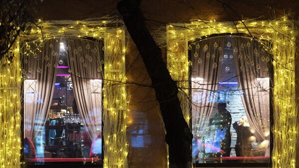 Силуэты людей в окне украшенного к Новому году кафе - Sputnik Казахстан