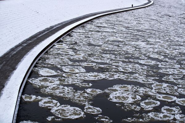 Ледяные блинчики украшают прогулку женщины вдоль замерзающей реки Нерис в Вильнюсе.  - Sputnik Казахстан