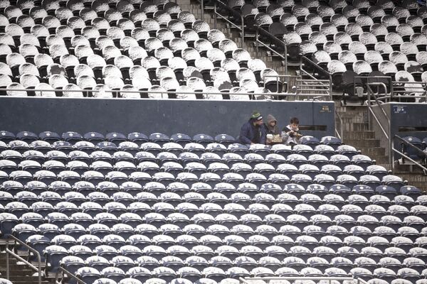 Трое болельщиков сидят вместе среди заснеженных сидений перед футбольным матчем в Сиэтле.  - Sputnik Казахстан