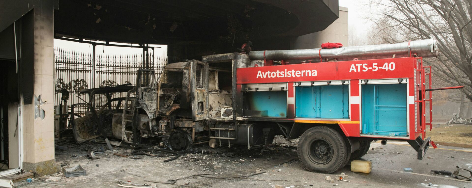 Сгоревшая пожарная машина изображена перед воротами административного здания в центре Алматы 6 января 2022 года - Sputnik Казахстан, 1920, 07.01.2022