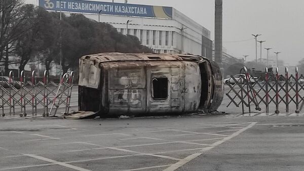 Перевернутая и сожженная инкассаторская машина у перегороженной площади Республики в Алматы  - Sputnik Казахстан