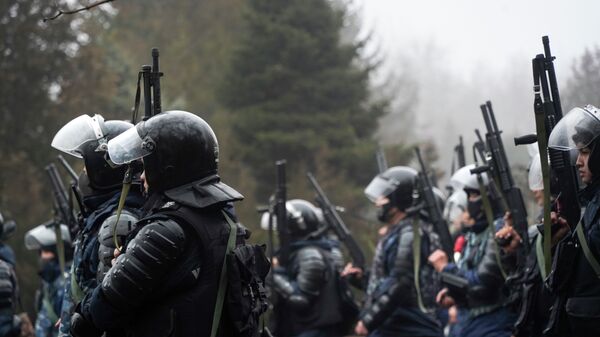 Омоновцы держат свое оружие наготове, пытаясь остановить демонстрантов во время акции протеста в Алматы, Казахстан, в среду, 5 января 2022 г.  - Sputnik Казахстан