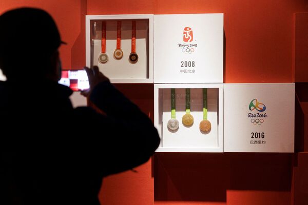 Ер адам 2008 жылы Бейжіңде өткен жазғы Олимпиада ойындарының медальдерін суретке түсіріп жүр.  - Sputnik Қазақстан