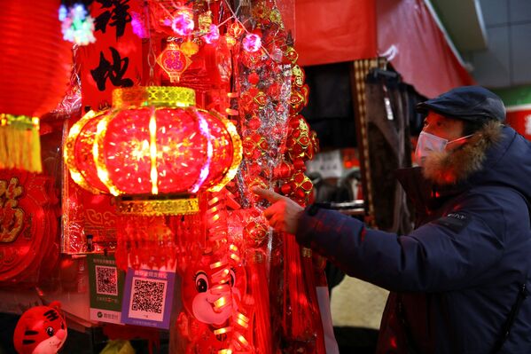 Покупатель смотрит на украшения для китайского Лунного Нового года на рынке в Пекине, Китай. - Sputnik Казахстан