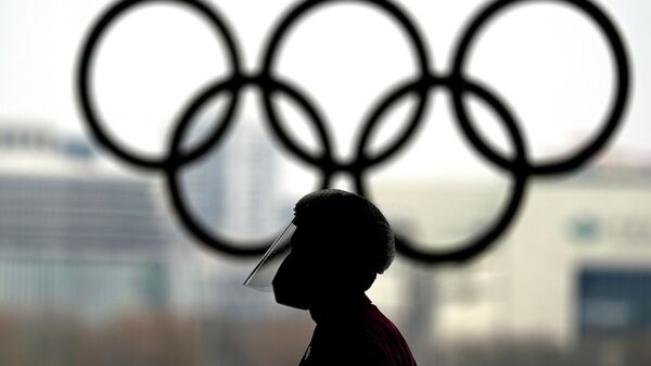 Человек в защитном экране на фоне олимпийских колец в Пекине - Sputnik Казахстан