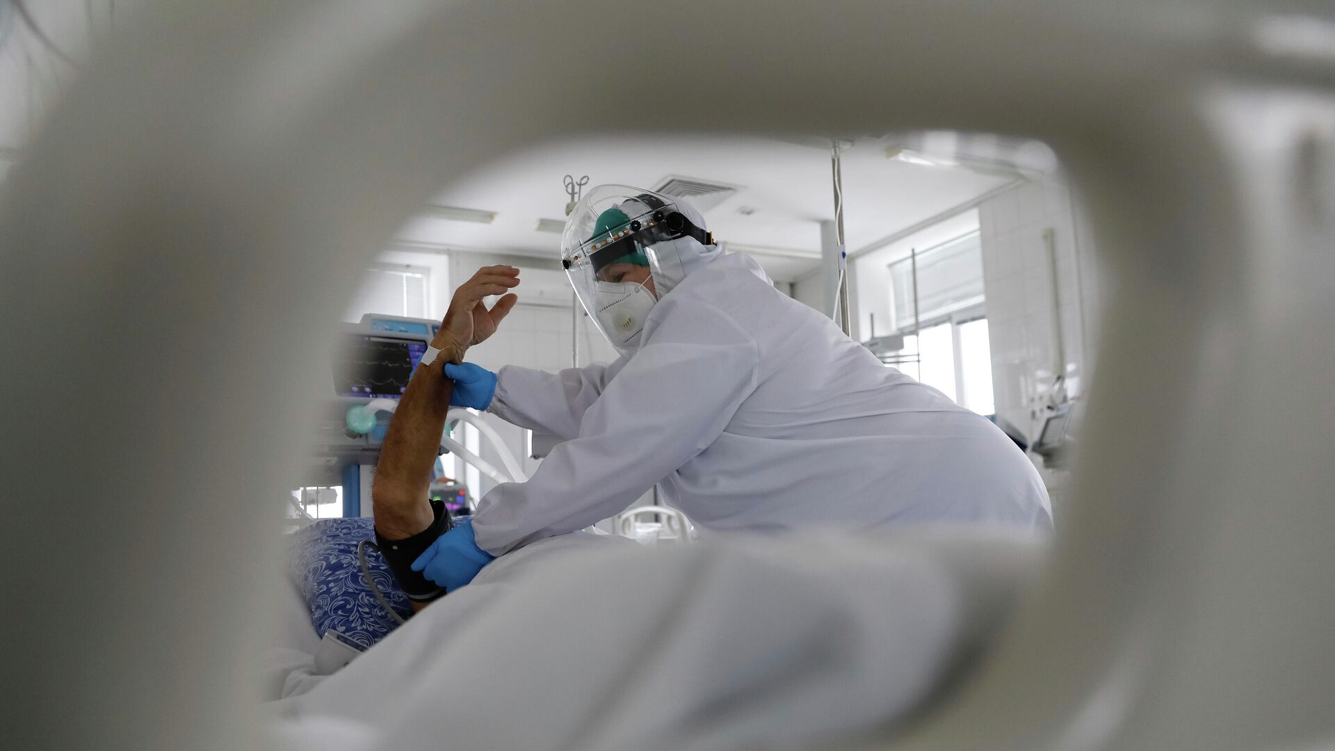 Медработник в защитном костюме измеряет давление у пациента в палате интенсивной терапии в больнице с коронавирусом  - Sputnik Казахстан, 1920, 17.05.2022