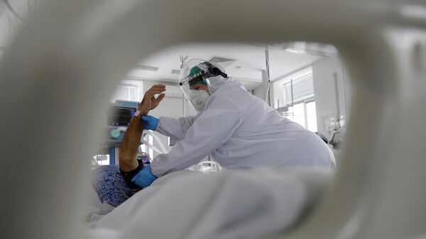 Медработник в защитном костюме измеряет давление у пациента в палате интенсивной терапии в больнице с коронавирусом  - Sputnik Қазақстан