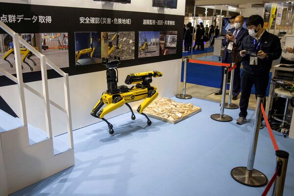 Сотрудник демонстрирует маневренного мобильного робота Spot® на Международной выставке роботов в Токио. - Sputnik Казахстан