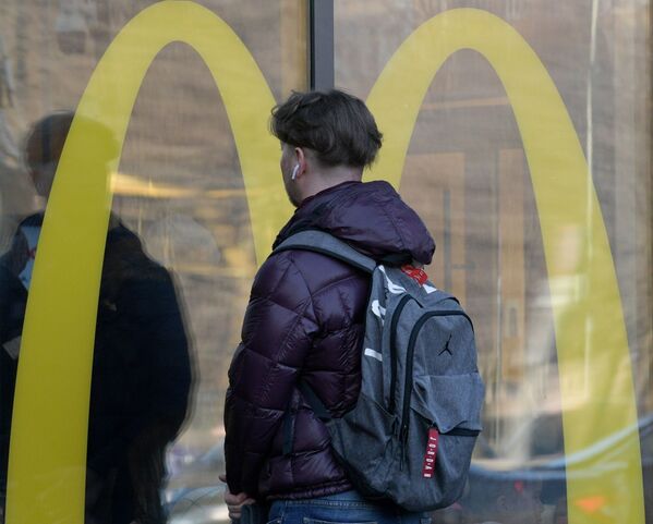 На фото: молодой человек стоит возле ресторана McDonald&#x27;s в Санкт-Петербурге, Россия.  - Sputnik Казахстан