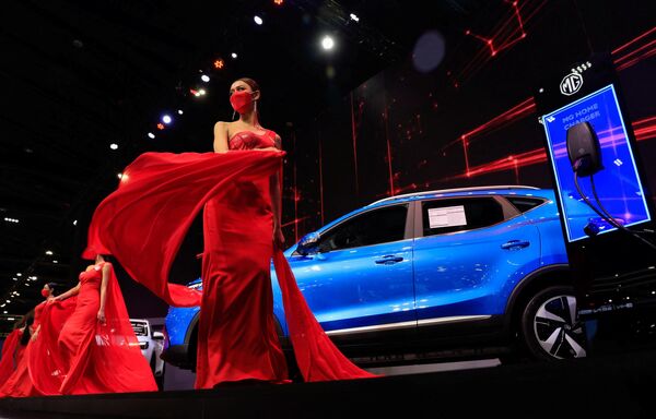Модели в красных платьях дефилируют рядом с автомобилем MGZS EV от MG Motor на Международном автосалоне в Бангкоке, Таиланд,. - Sputnik Казахстан