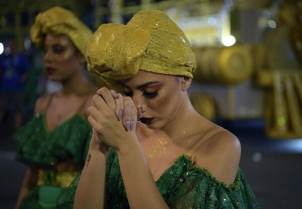 Танцовщица школы самбы Imperatriz Leopoldinense молится перед выступлением во время первой ночи карнавальных парадов на самбадроме Marques de Sapucai в Рио-де-Жанейро, Бразилия. - Sputnik Казахстан
