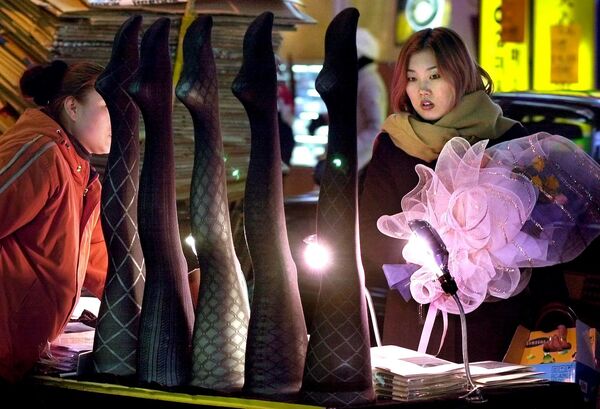 Девушка рассматривает чулки на прилавке уличного торговца в Сеуле, Южная Корея, 2001 год. - Sputnik Казахстан
