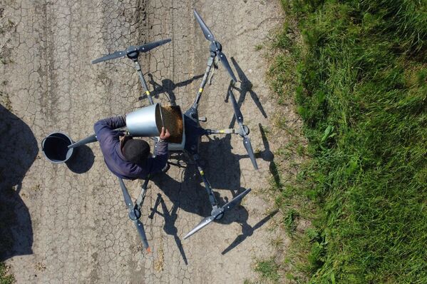 Рисовод Темрюкского района засыпает зерно в отсек дрона перед началом засеивания поля рисом.  - Sputnik Казахстан