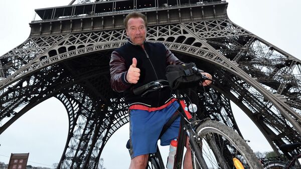 Американский актер и политик Арнольд Шварценеггер позирует под Эйфелевой башней после поездки на велосипеде по Парижу - Sputnik Қазақстан