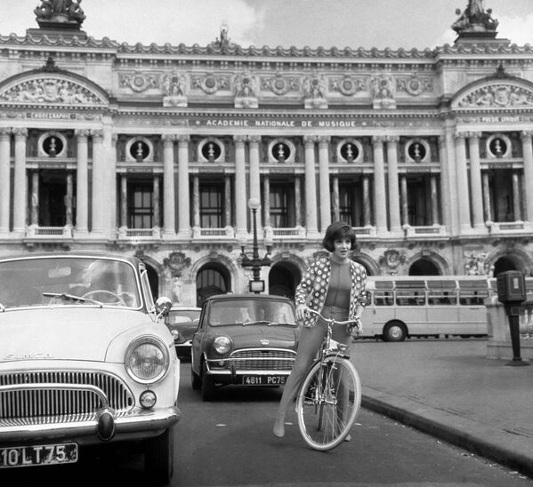 Итальянская актриса Джина Лоллобриджида едет на велосипеде на площади Оперы в Париже, 1964 год.  - Sputnik Казахстан