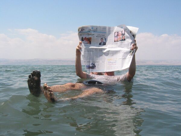 Человек может лежать на поверхности Мертвого моря - настолько плотная здесь вода.  - Sputnik Казахстан