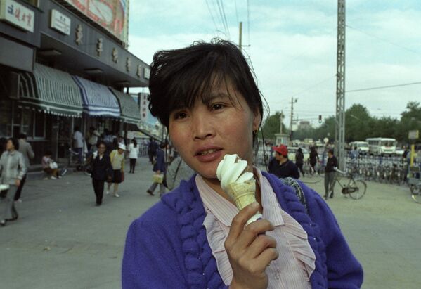 Бейжің көшелерінің бірі, Қытай Халық Республикасы. Бейжің тұрғыны 1990 жылдың 20 маусымында көшеде балмұздақпен суретке түсіп тұр - Sputnik Қазақстан