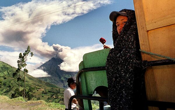 Патате жанында Тунгурауа вулканы түтіндеп жатқан шақта әйел оранып алып балмұздақ жеп отыр, 1999 жылдың 11 қарашасы, Эквадор - Sputnik Қазақстан