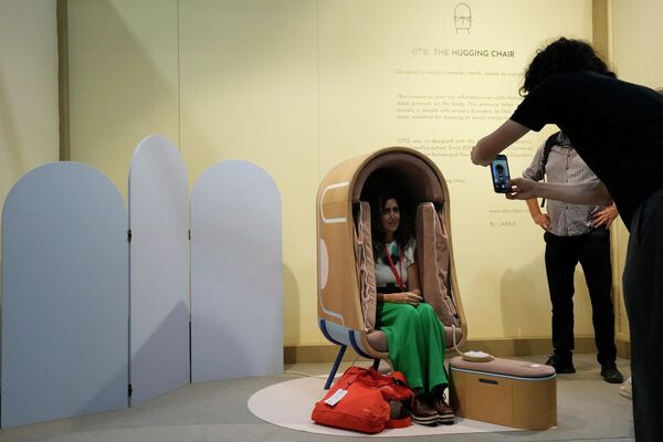 Мужчина фотографирует женщину, сидящую на стуле, созданном дизайнерами мебели Oto в рамках выставки Design Fair в Милане. - Sputnik Казахстан