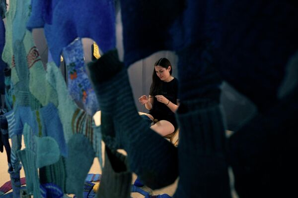 Женщина из Латвийской академии художеств чинит носки в рамках выставки Design Fair в Милане. - Sputnik Казахстан