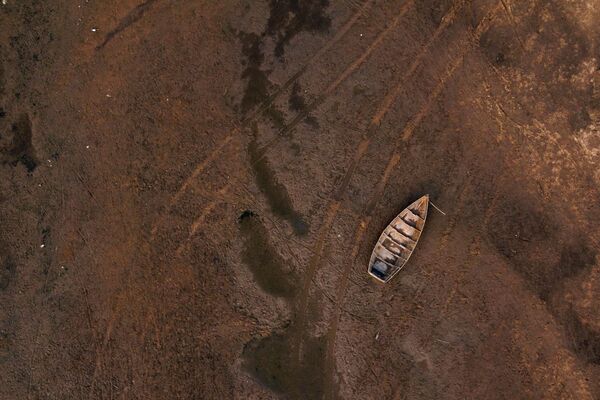 Следы от автомобиля на дне реки возле севшей на мель лодки на реке Парана (Аргентина). Уровень воды в ней достиг исторического минимума. - Sputnik Казахстан