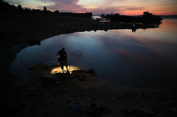 Рыбак стоит на берегу обмелевшего озера Поянху в Цзюйцзяне. - Sputnik Казахстан