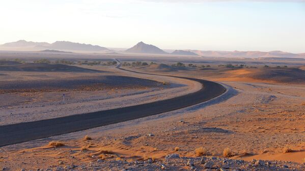 Намибия шөліндегі Соссусфлейге апаратын жолдың көрінісі. Тас жолдың айналасын құм төбелері қоршап тұр. - Sputnik Қазақстан