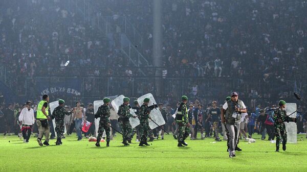 Военнослужащие индонезийской армии охраняют поле после футбольного матча между футбольными клубами Arema FC и Persebaya Surabaya на стадионе Kanjuruhan - Sputnik Казахстан
