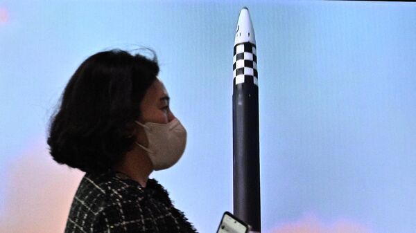 Женщина проходит мимо телевизионного экрана во время трансляции запусков баллистических ракет на железнодорожной станции Сеула  - Sputnik Казахстан