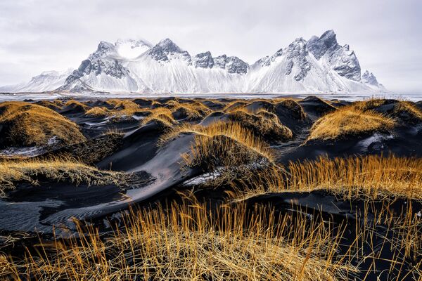 Снимок итальянского фотографа Ивана Педретти. Зима в исландском Стоккснесе на пляже с черным песком и величественной горой Вестрахорн. Его особенностью является игра цветов и контрастов. - Sputnik Казахстан