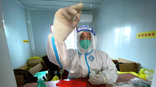 Медик в защитном костюме работает с ПЦР-тестами на коронавирус - Sputnik Казахстан