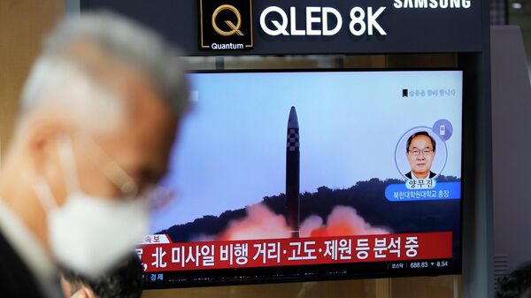 Жители Сеула проходят мимо монитора, на котором транслируется запуск северокорейской ракеты  - Sputnik Казахстан