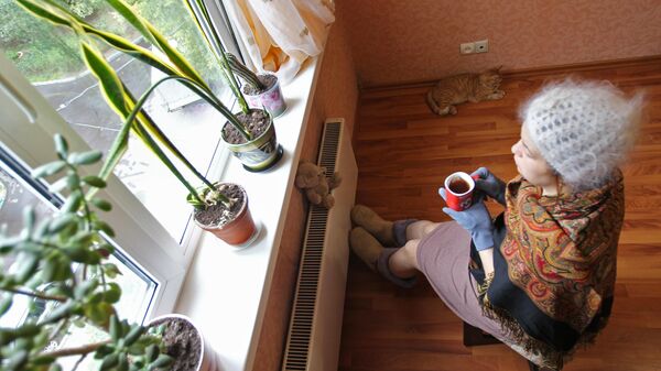 :tyobyf сидит в теплой одежде у батареи в квартире. Архивное фото - Sputnik Казахстан
