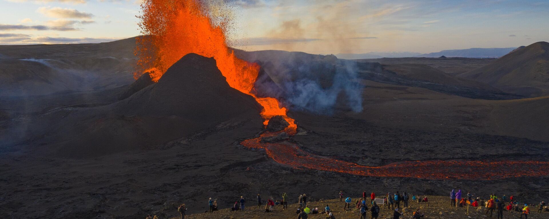 Люди наблюдают, как лава вытекает из извержения вулкана Фаградальсфьялл на полуострове Рейкьянес, Исландия - Sputnik Казахстан, 1920, 04.12.2023