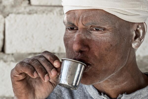 На севере Африки, в Египте предпочитают очень крепкий черный чай, к нему подается стакан воды. Здесь предпочитают черный чай из Кении, Малави или Цейлона, причем в южных районах страны чай делают очень крепким путем его варки в течение 5 минут. К чаю в Египте нередко добавляют мяту или молоко. На фото: египтянин пьет чай в перерыве на обед в городе Минья.  - Sputnik Казахстан