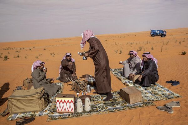 Арабы пьют чай из маленьких чашечек, расширяющихся кверху. Приготовлением напитка занимаются мужчины. Арабы пьют только зеленый чай, потому что религия запрещает им употребление ферментированных напитков. На фото: местные жители пьют чай и кофе на песчаных дюнах в Саудовской Аравии. - Sputnik Казахстан