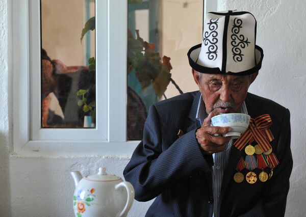 На юге Кыргызстана чай подают в маленьких пиалах, чтобы он всегда оставался горячим. На Иссык-Куле любят пить из больших чынов (пиал). А в Таласе и Нарыне воду для чая принято кипятить в самоорах (самоварах). В куурма чай добавляют молоко, проросшую пшеницу и обжаренную муку. На фото: 93-летний ветеран Второй мировой войны Сардар Акылбеков пьет чай в своем доме в селе Ток-Бай, Кыргызстан.  - Sputnik Казахстан