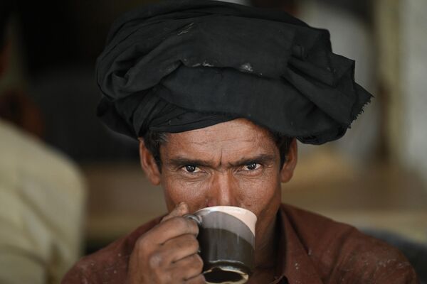 В Пакистане любят пить черный чай с молоком и кучей сахара, также пьют &quot;Кава&quot; - зеленый чай с кардамоном, шафраном и корицей и кашмирский розовый чай. Его варят в самоварах и пьют, как в Монголии или Тибете - с маслом и солью. На фото: мужчина пьет чай в придорожном ресторане в Исламабаде,. - Sputnik Казахстан